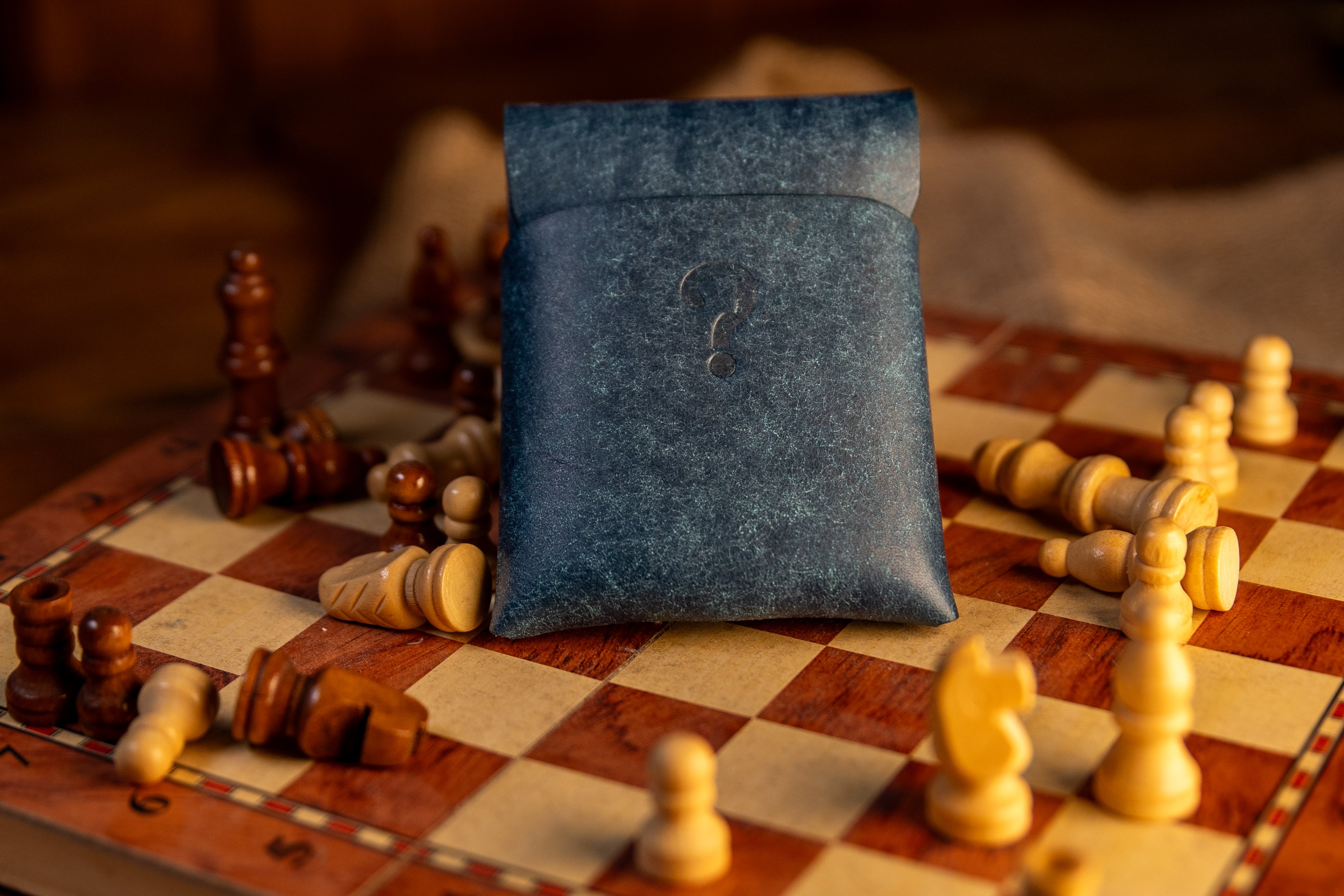 Blue pueblo leather wallet on a chessboard with scattered chess pieces