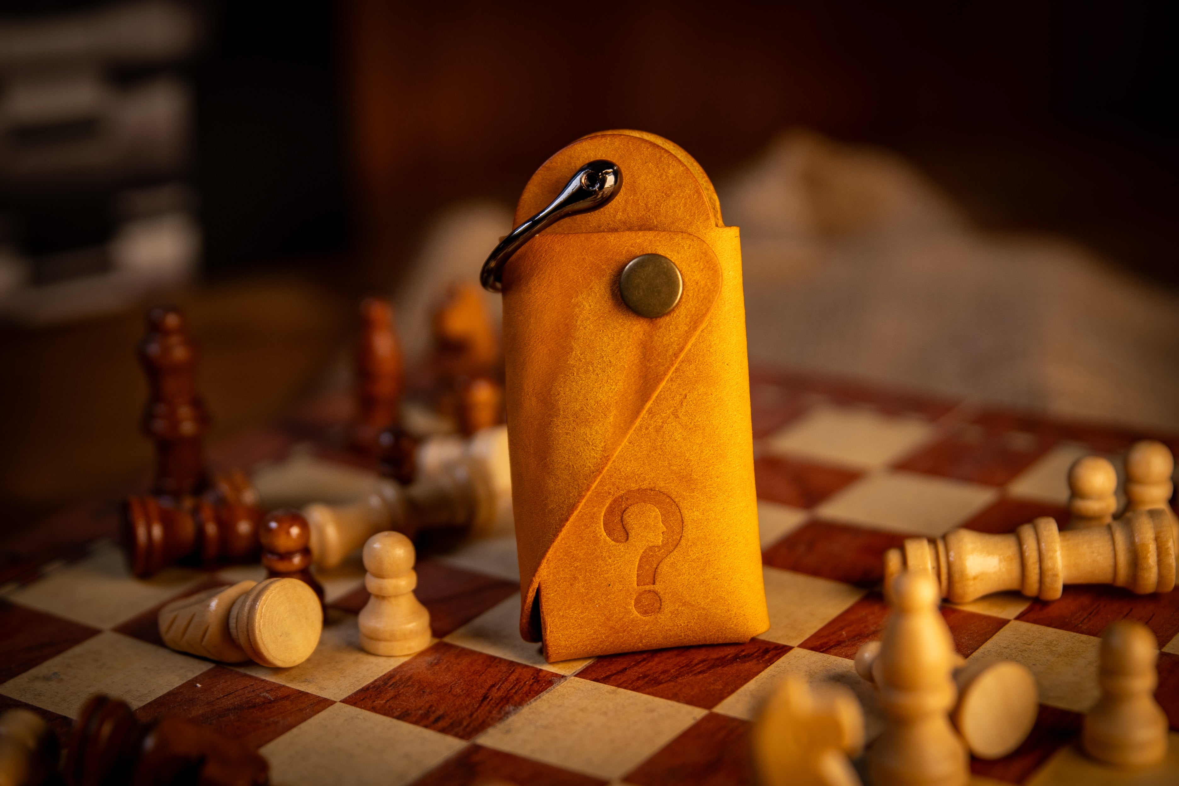 Yellow key organiser with a question mark on a chessboard with scattered chess pieces.