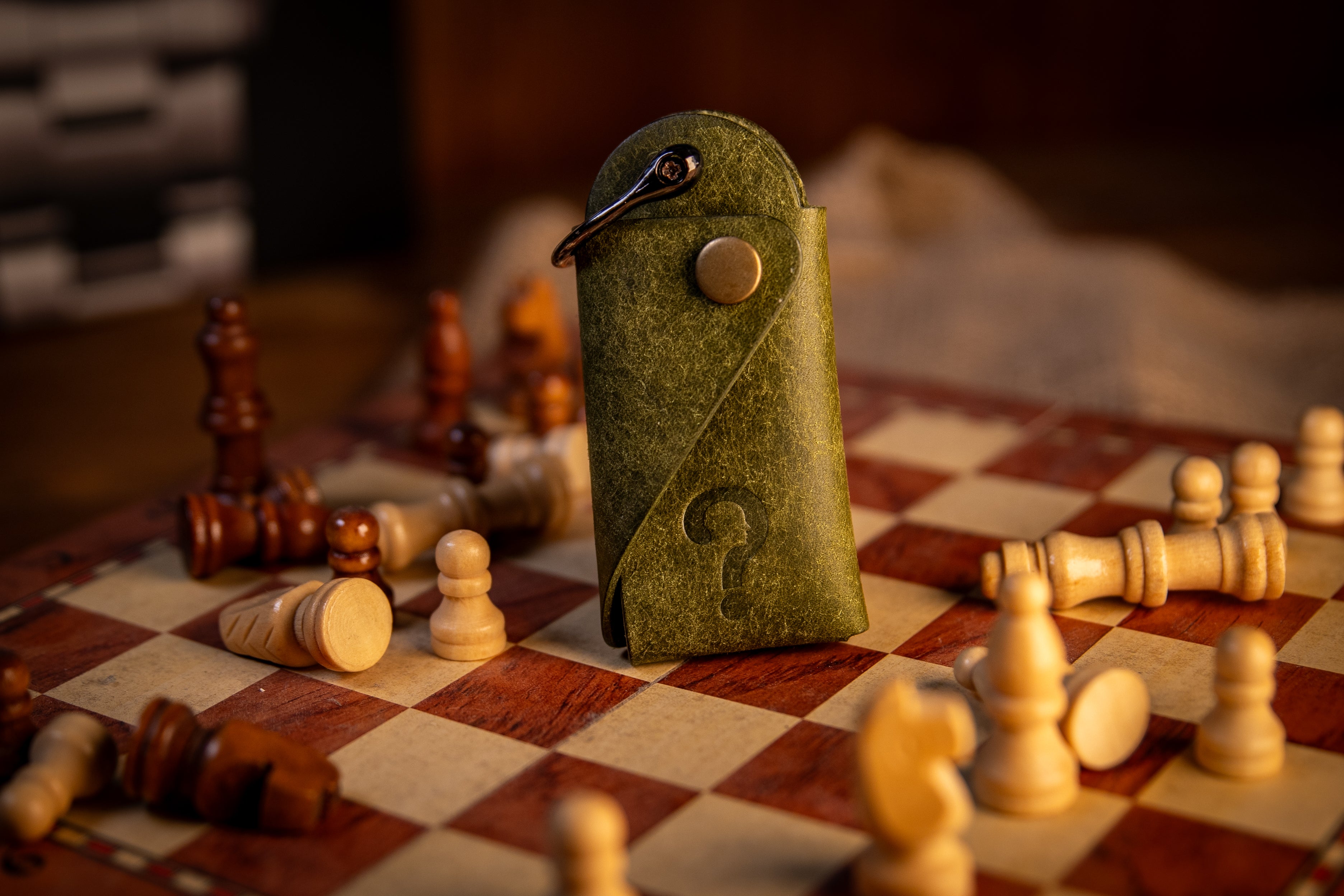 Green leather key organiser pouch on a chessboard with chess pieces around