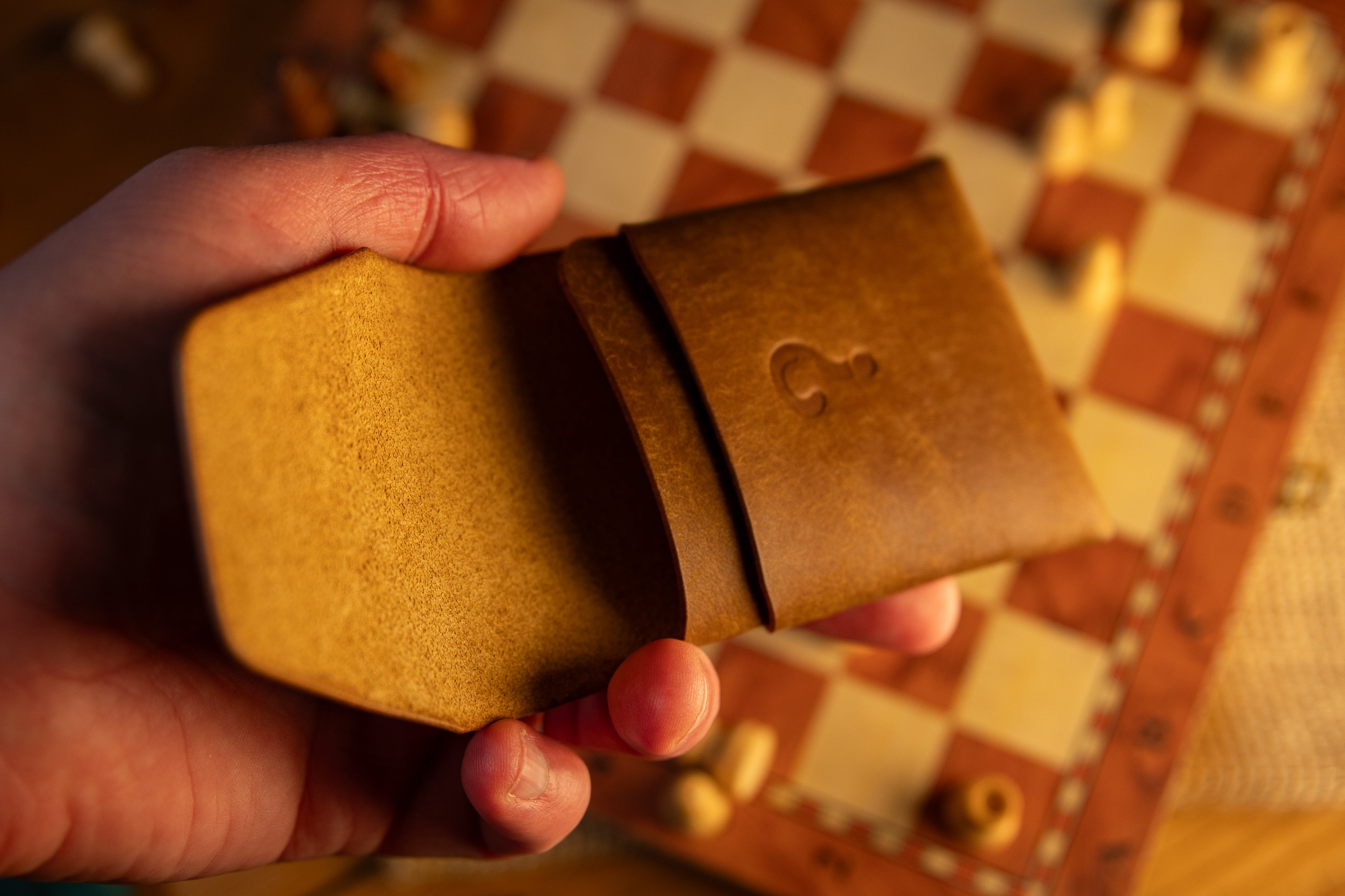 Hand holding a brown pueblo leather wallet with a checkered background