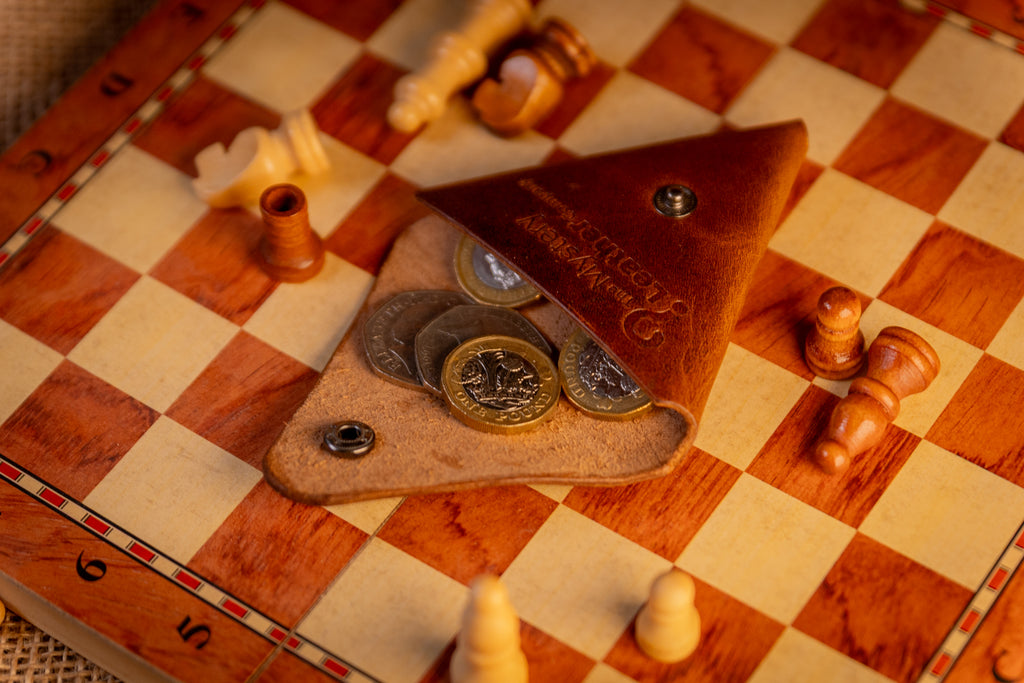 Small leather pouch with coins on a chessboard