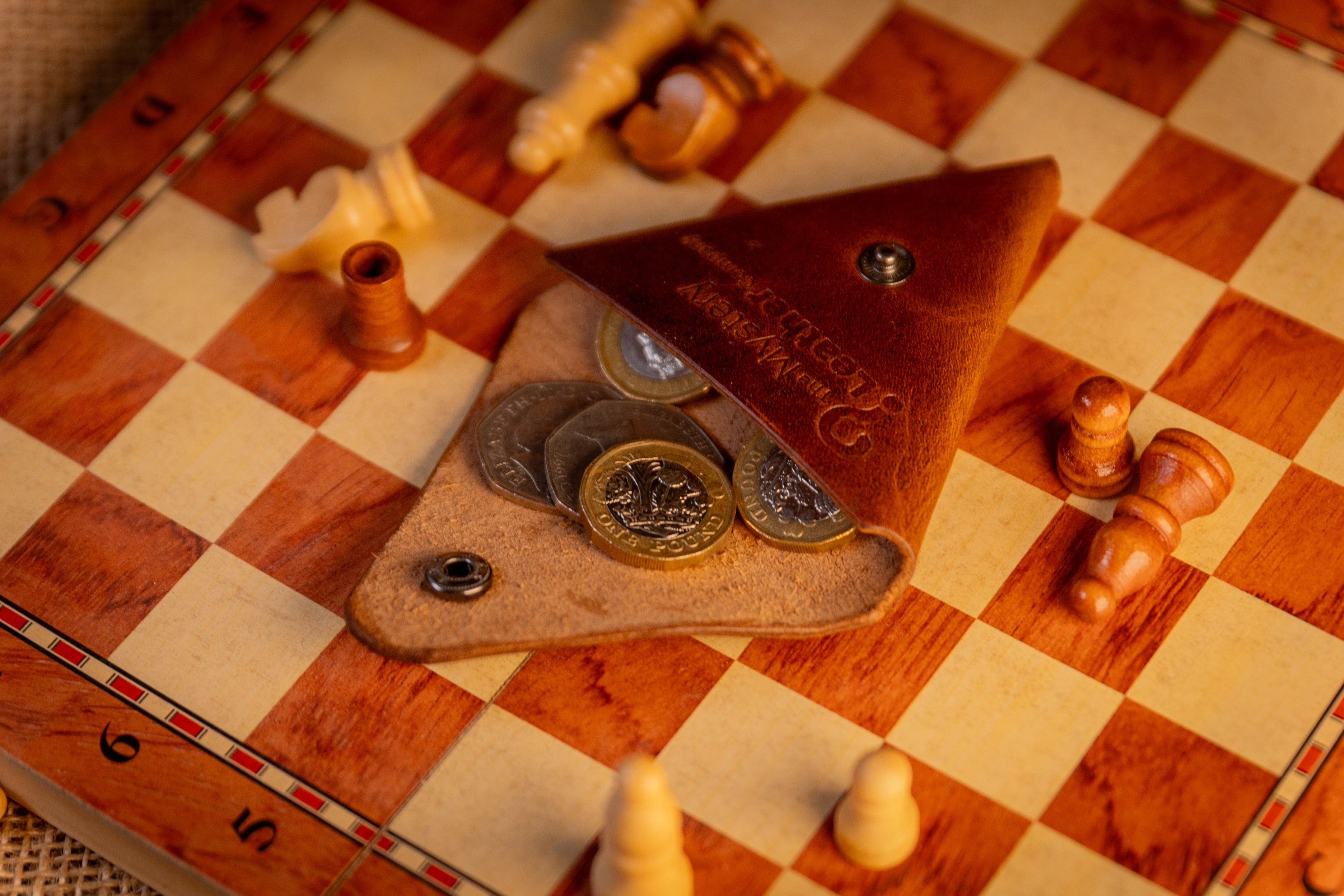 Small leather pouch with coins on a chessboard
