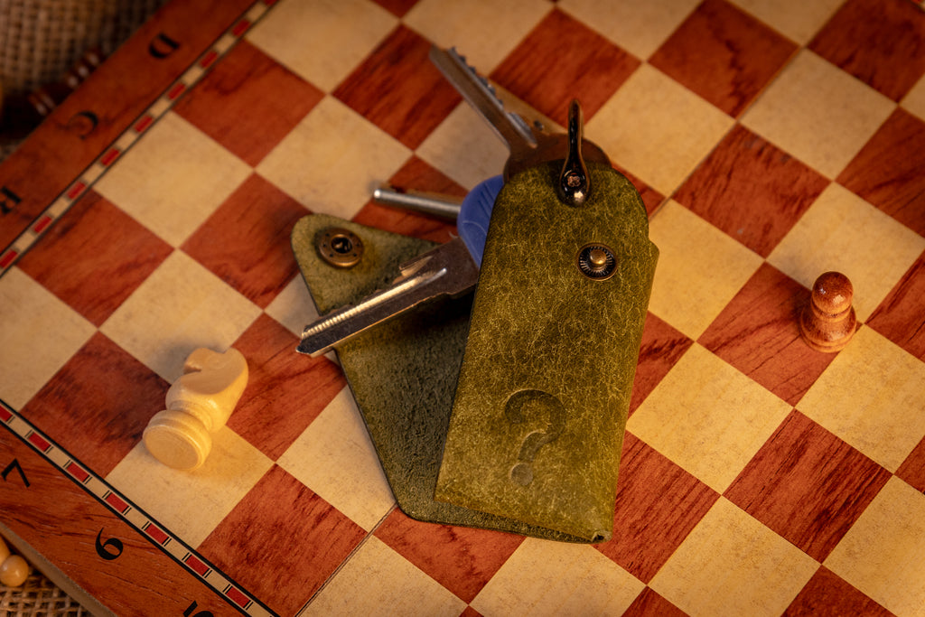 Green leather wallet with metal clip on a checkered wooden surface