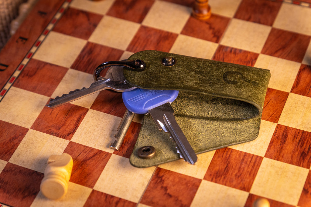 Green leather key organiser with keys on a checkered wooden surface
