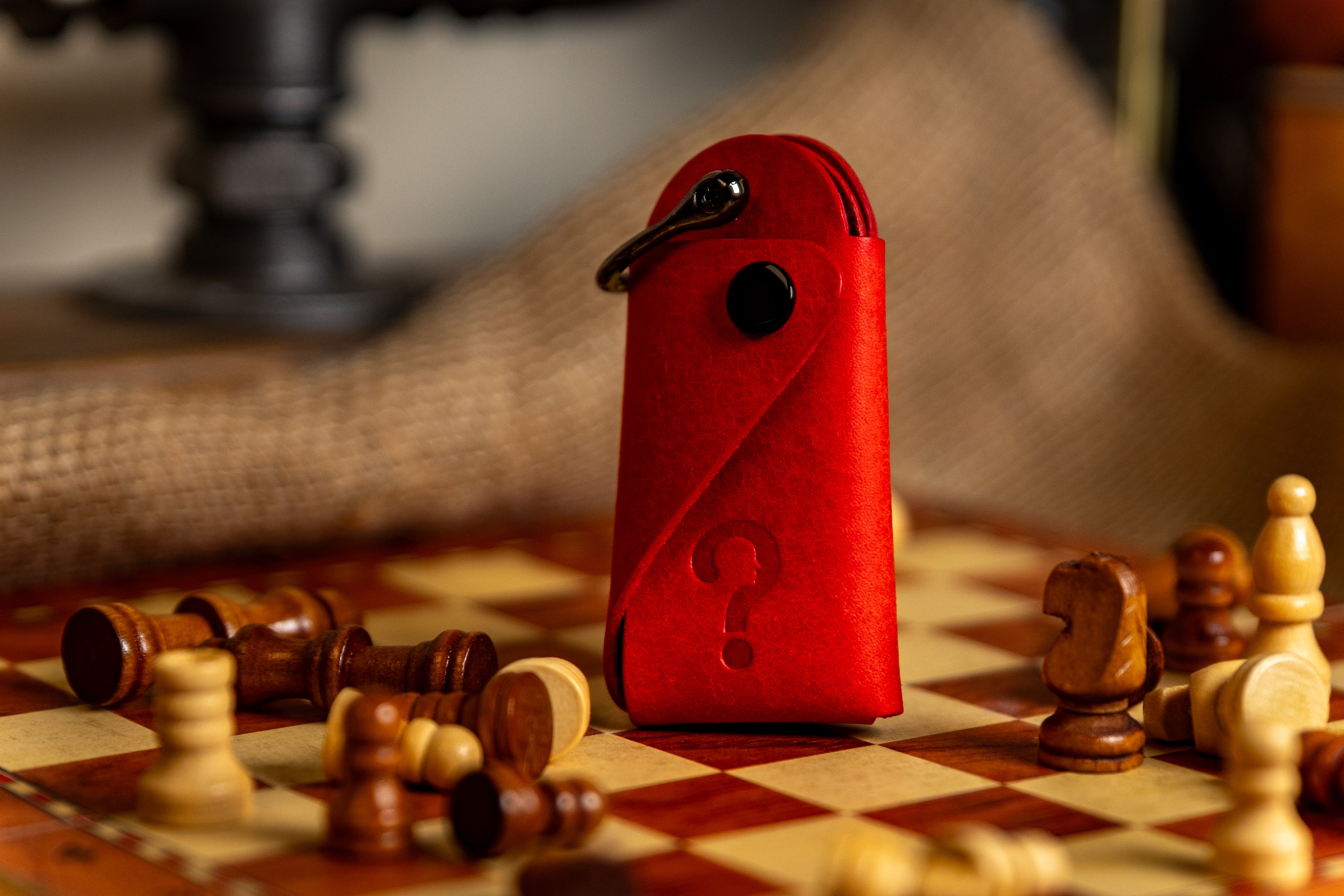 Red leather key case with a keychain on a chessboard