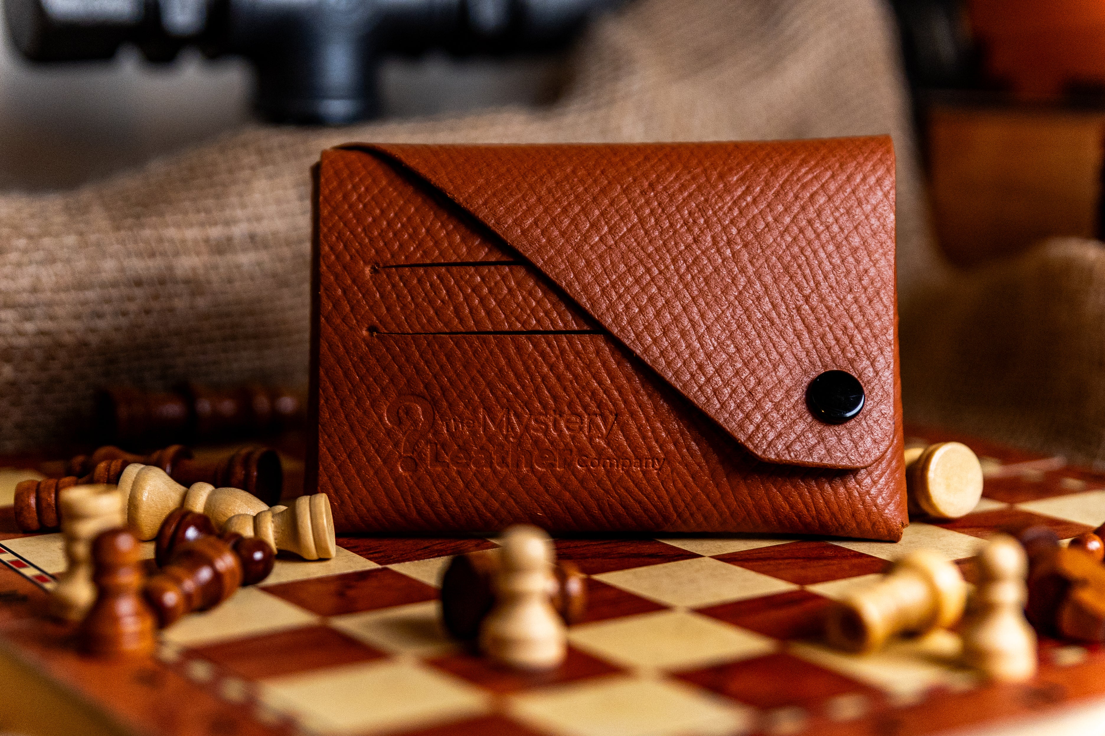 Brown leather wallet on a chessboard with game pieces