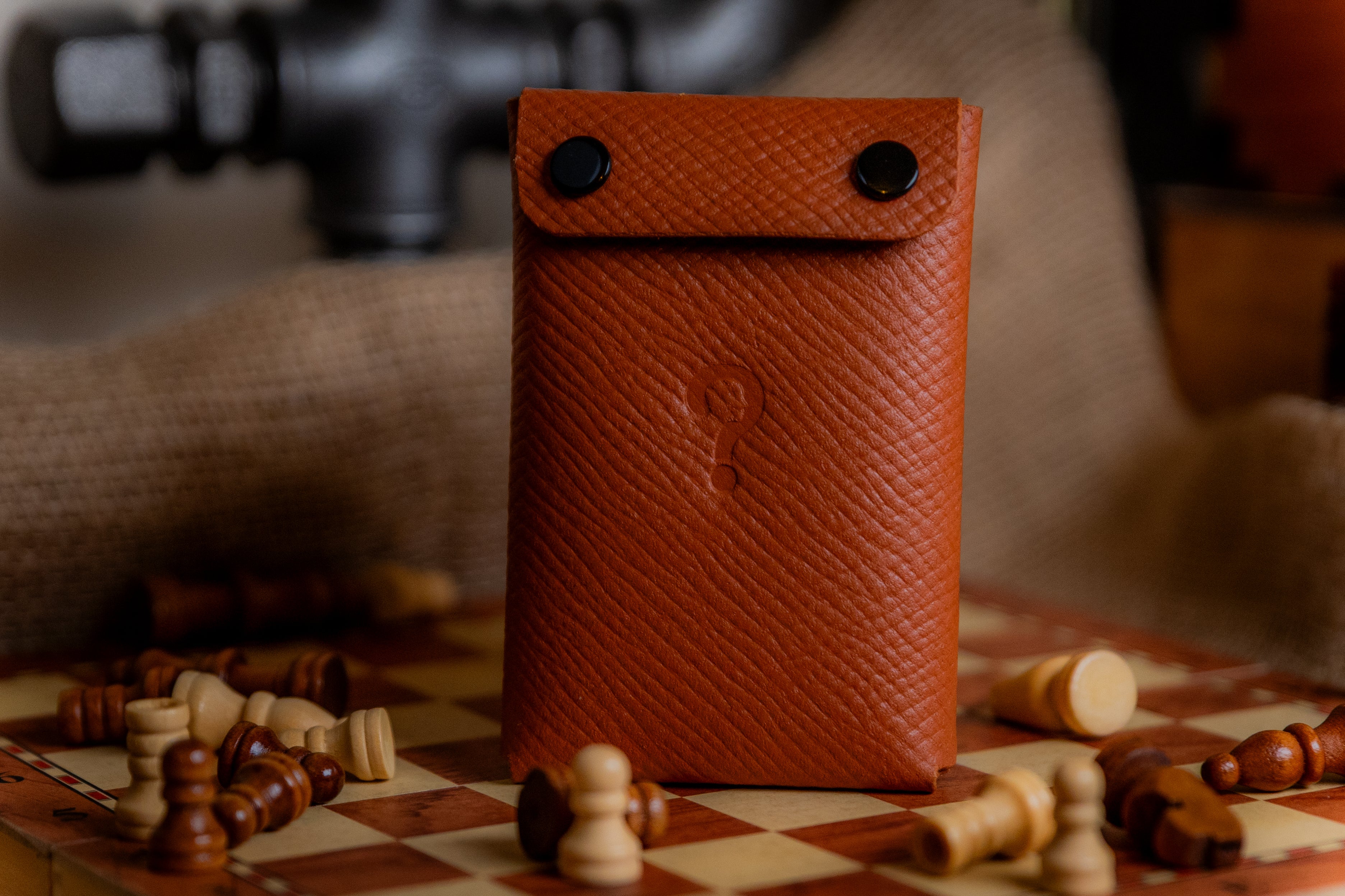 Brown leather wallet on a chessboard with chess pieces