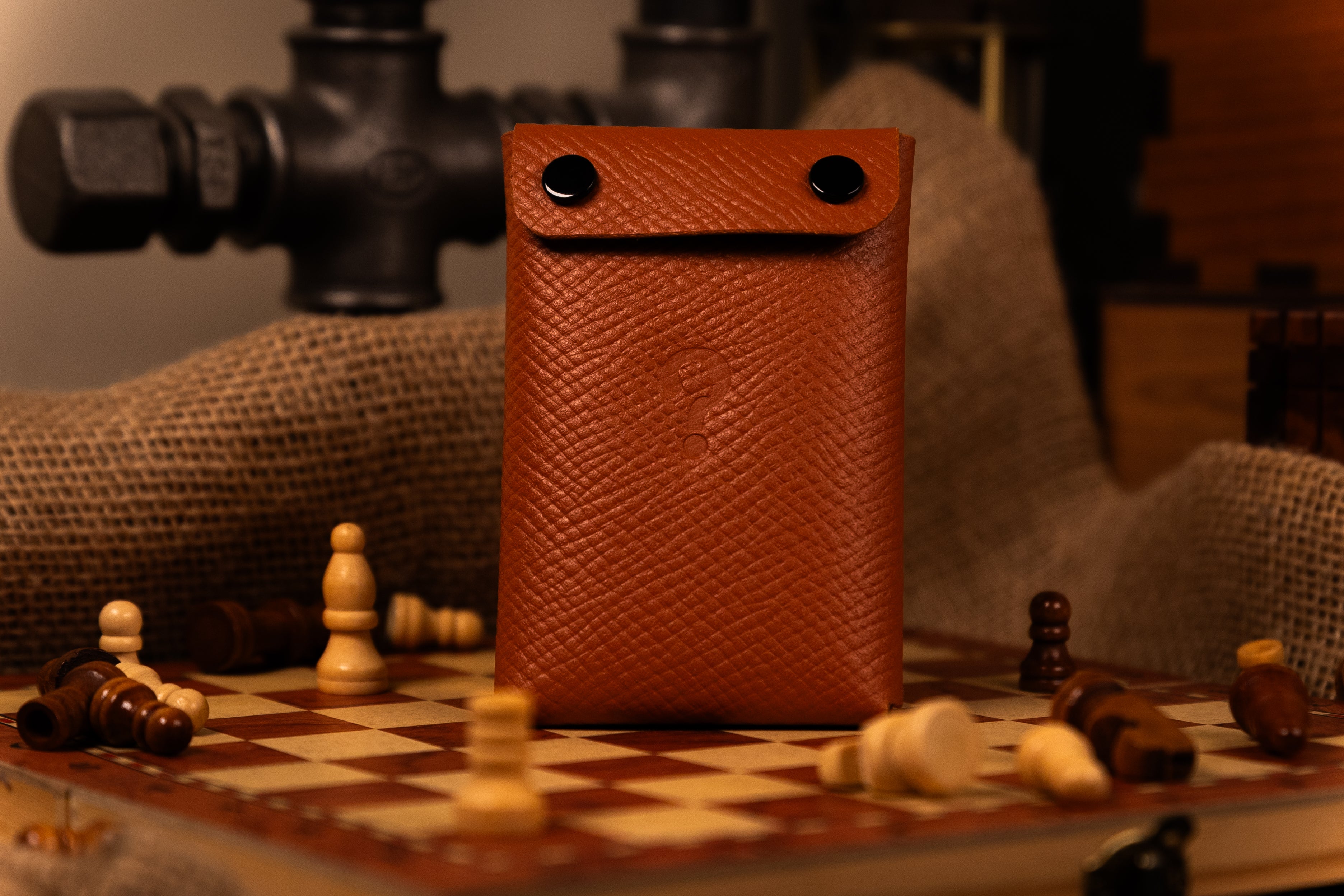 Brown leather pouch on a chessboard with chess pieces