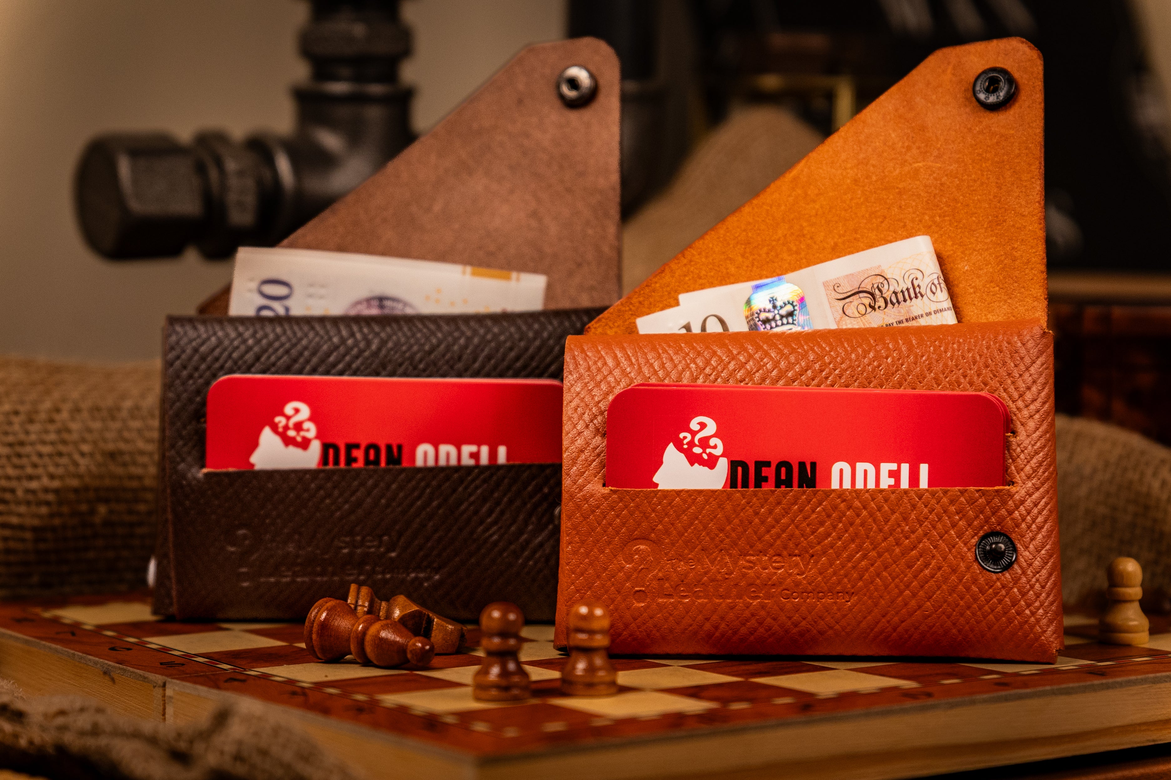 Two wallets, one black and one orange, with visible brand name on a checkered surface.