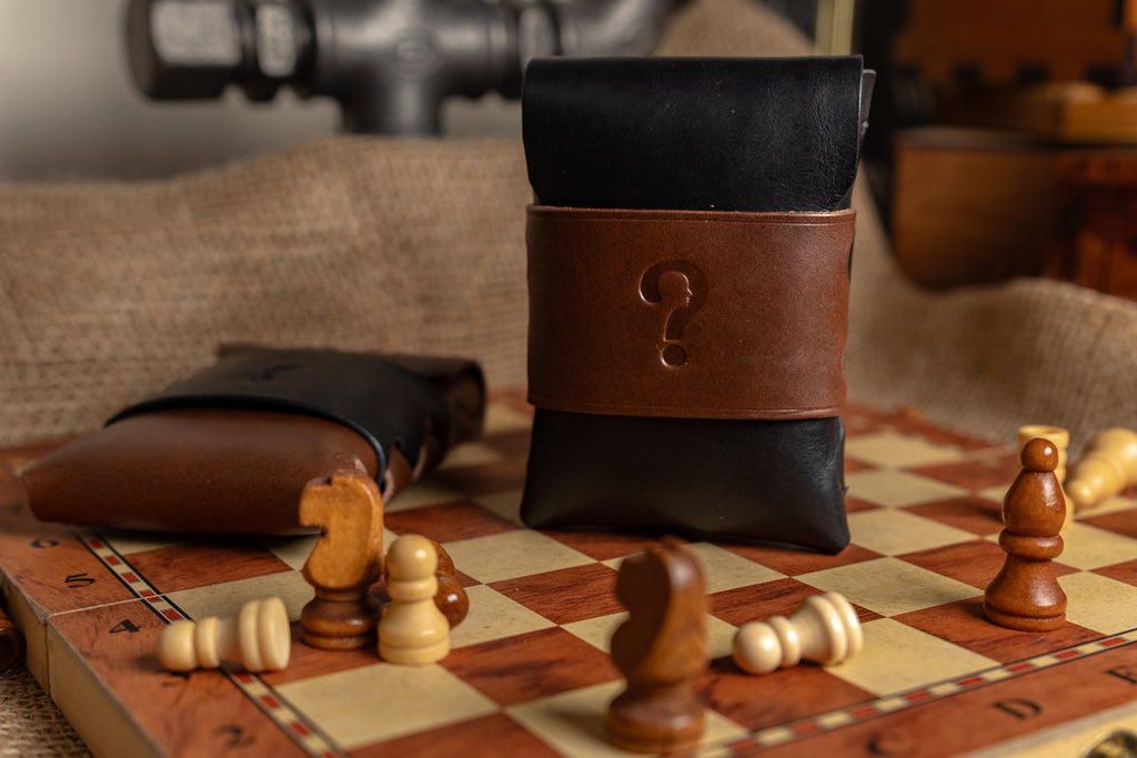 Brown walpier buttero leather pouch with black top on a chessboard with chess pieces.