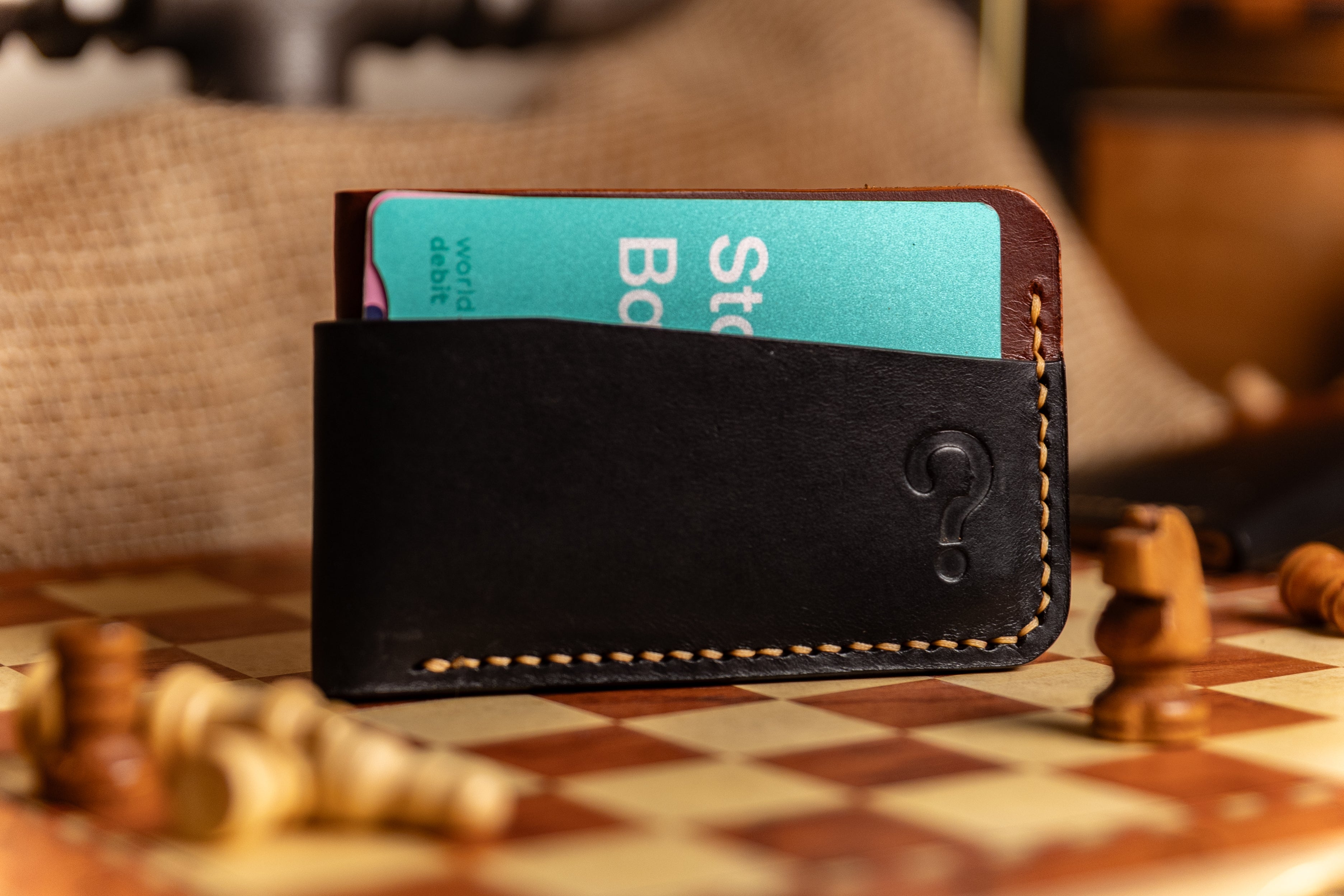 Black leather wallet with a turquoise card on a chessboard