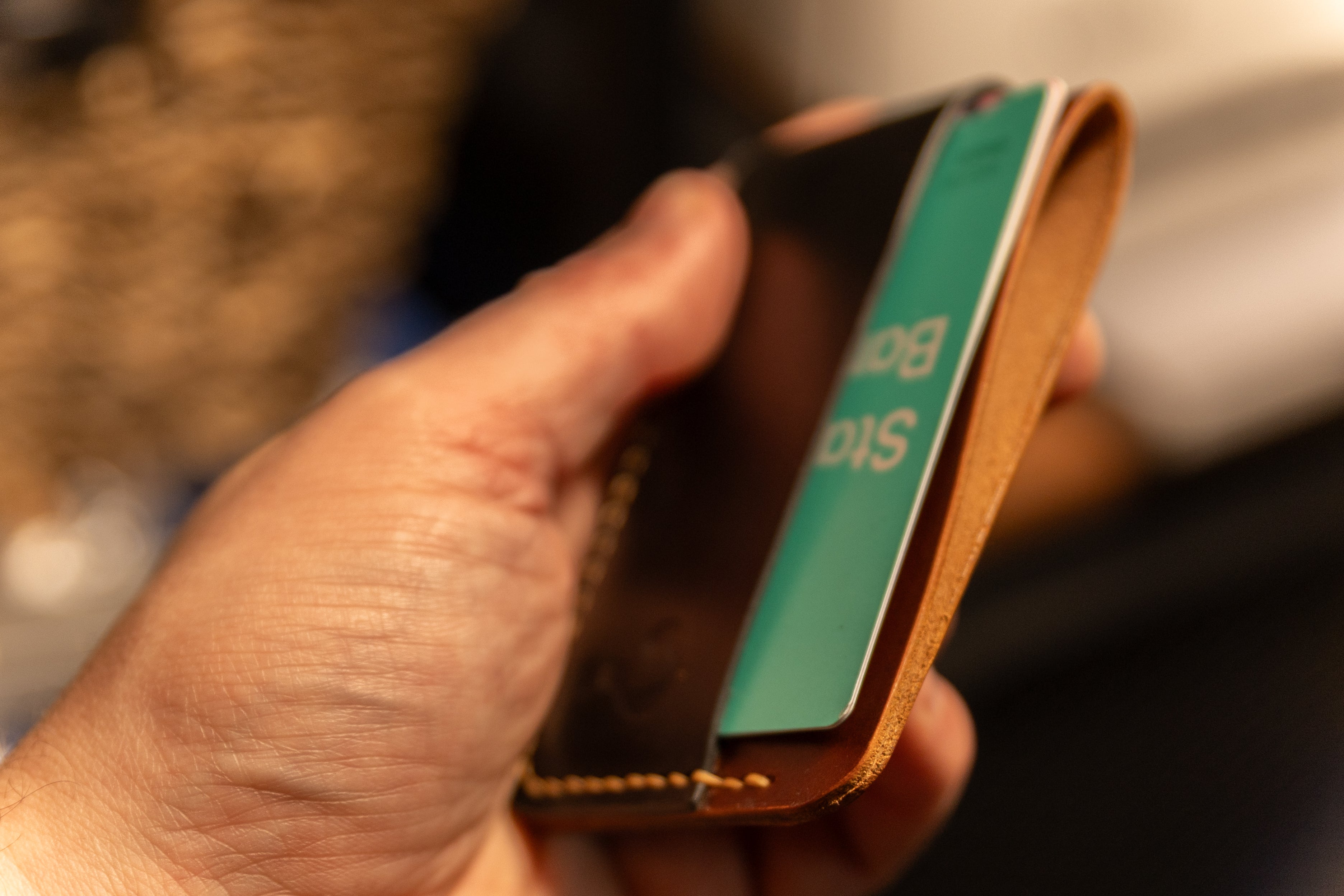 Hand holding a leather wallet with a blurred background