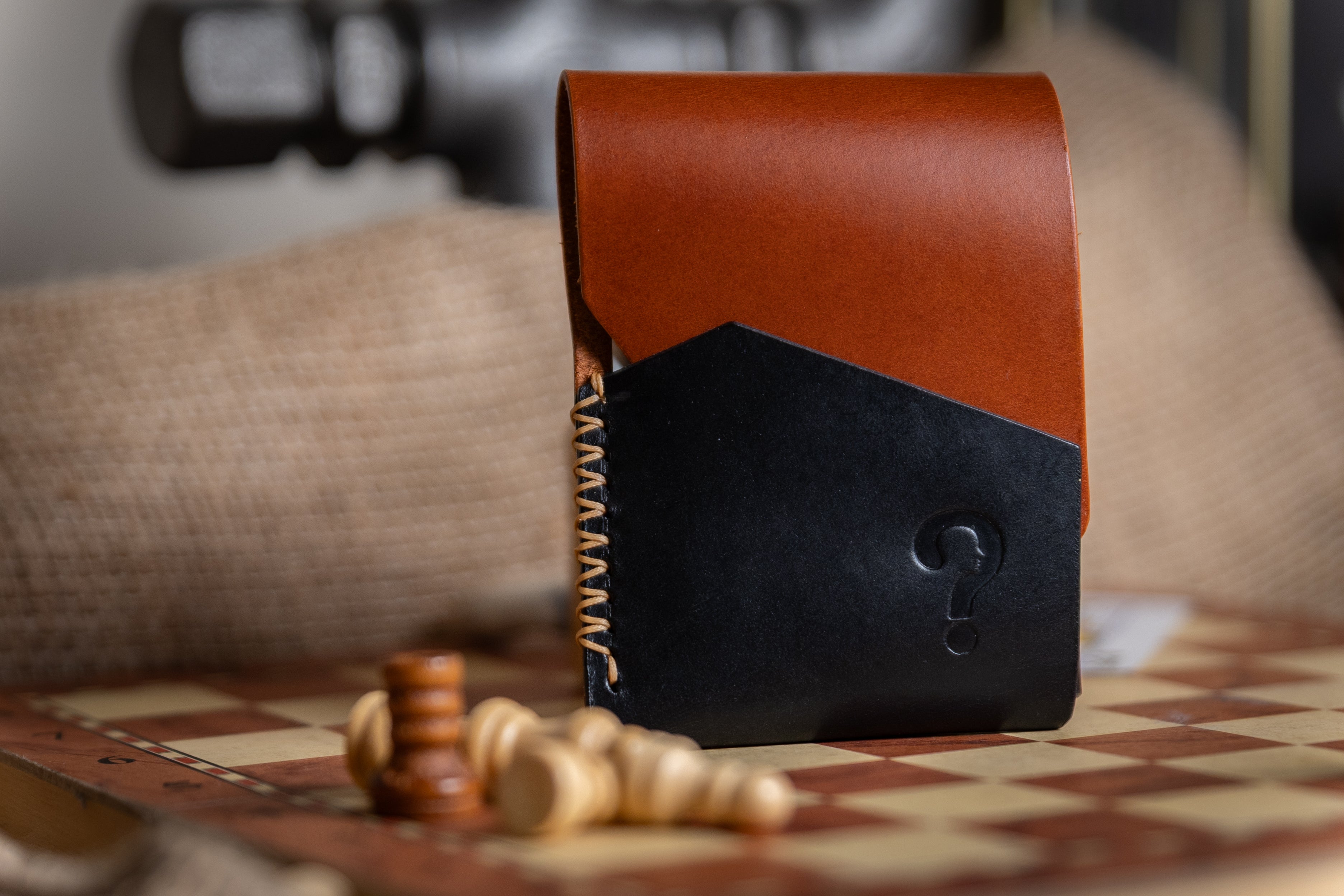 Two-tone leather wallet with brown top and black bottom on a checkered surface.