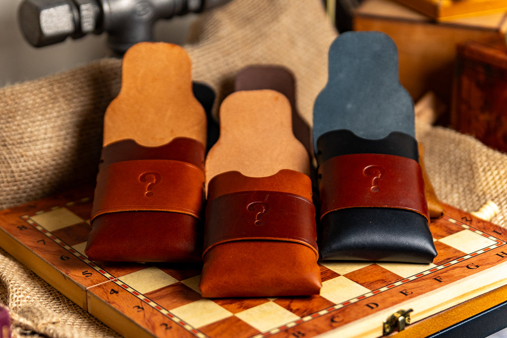 Three walpier buttero leather cases with question marks on a checkered surface