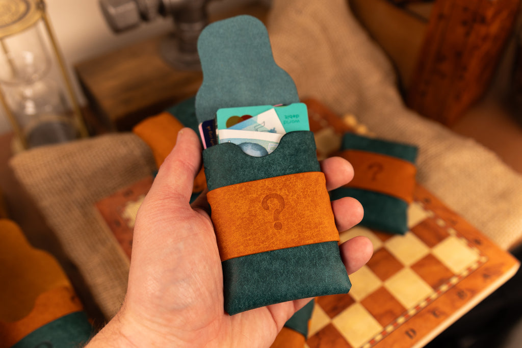 Hand holding a teal and brown pueblo leather wallet with a question mark design.