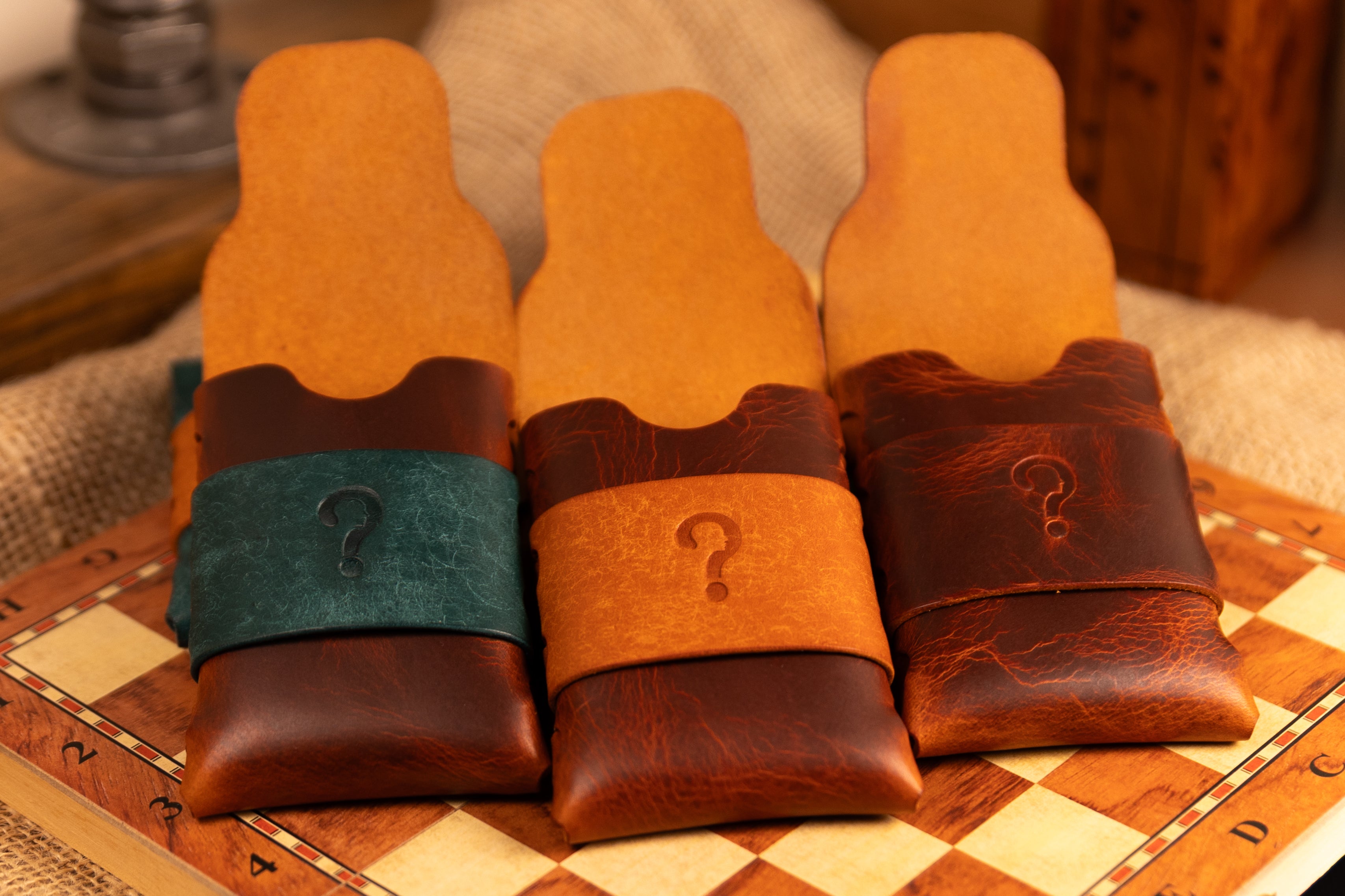 Three wax leather wallets with question marks on a checkered surface