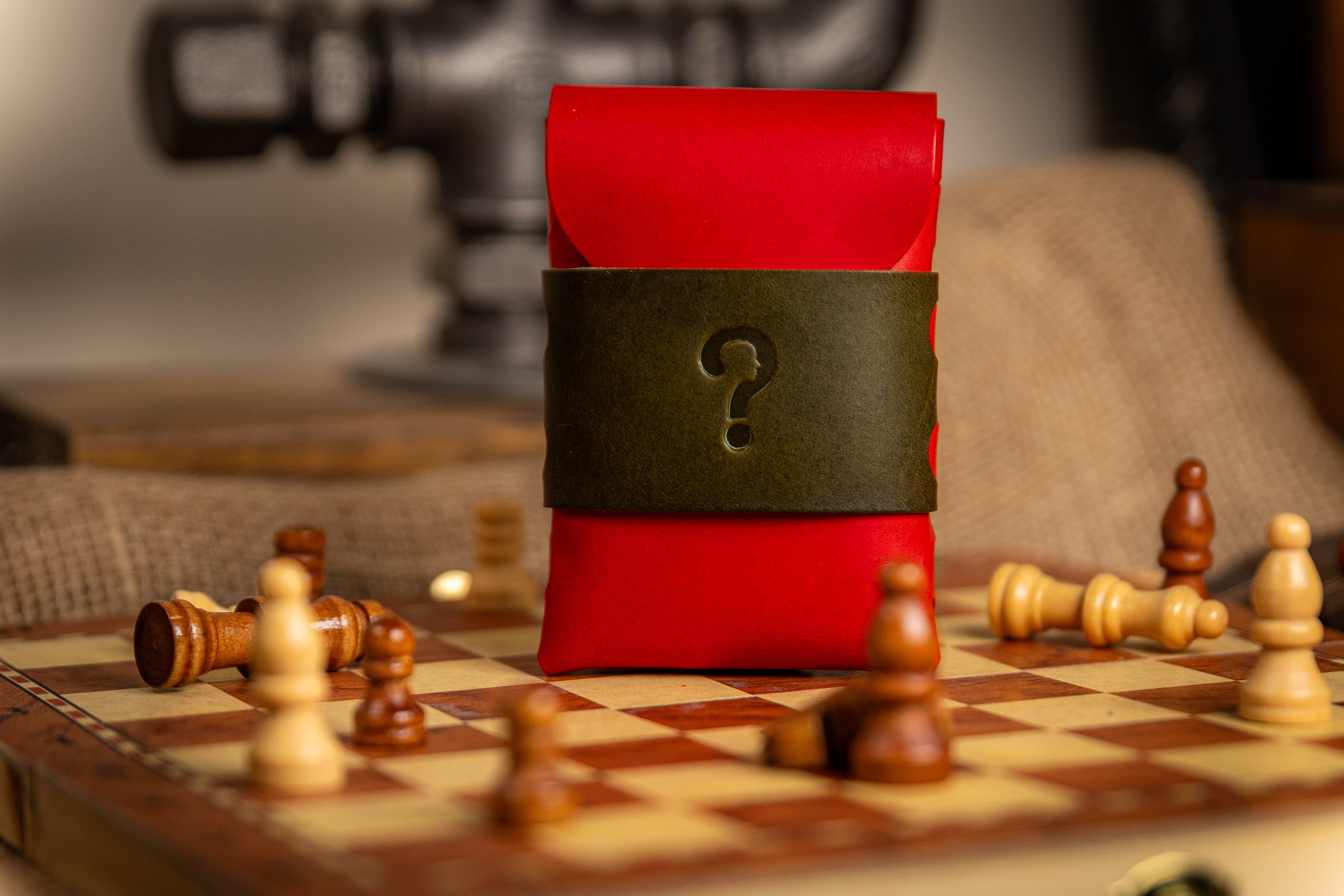 Red walpier buttero leather wallet pouch with a question mark on a chessboard with fallen pieces