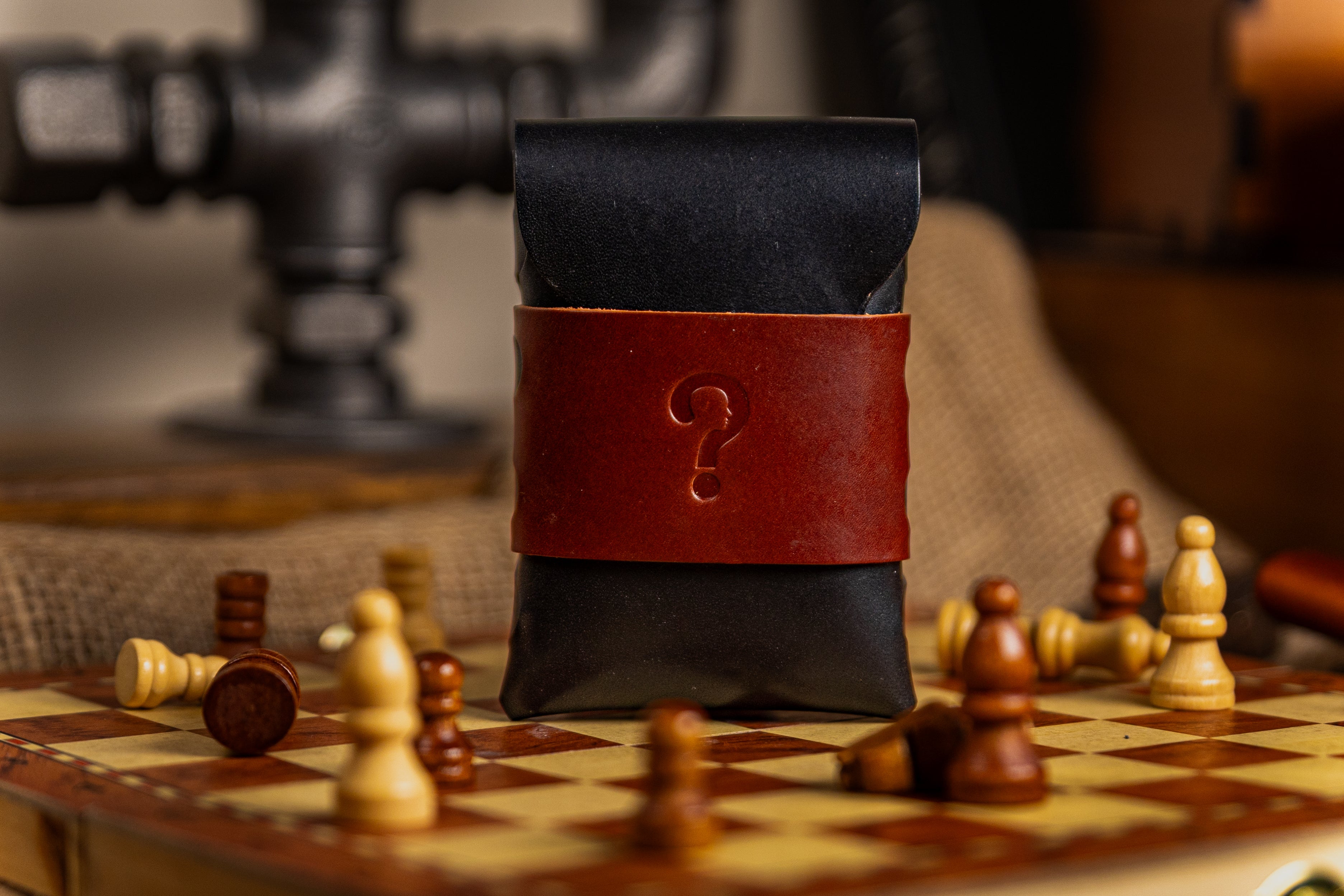 Black walpier buttero leather wallet pouch with a red strap featuring a question mark on a chessboard.