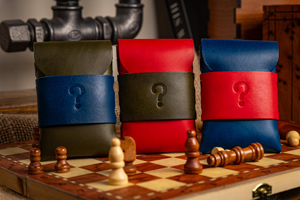 Three walpier buttero leather pouches with question marks on a chessboard