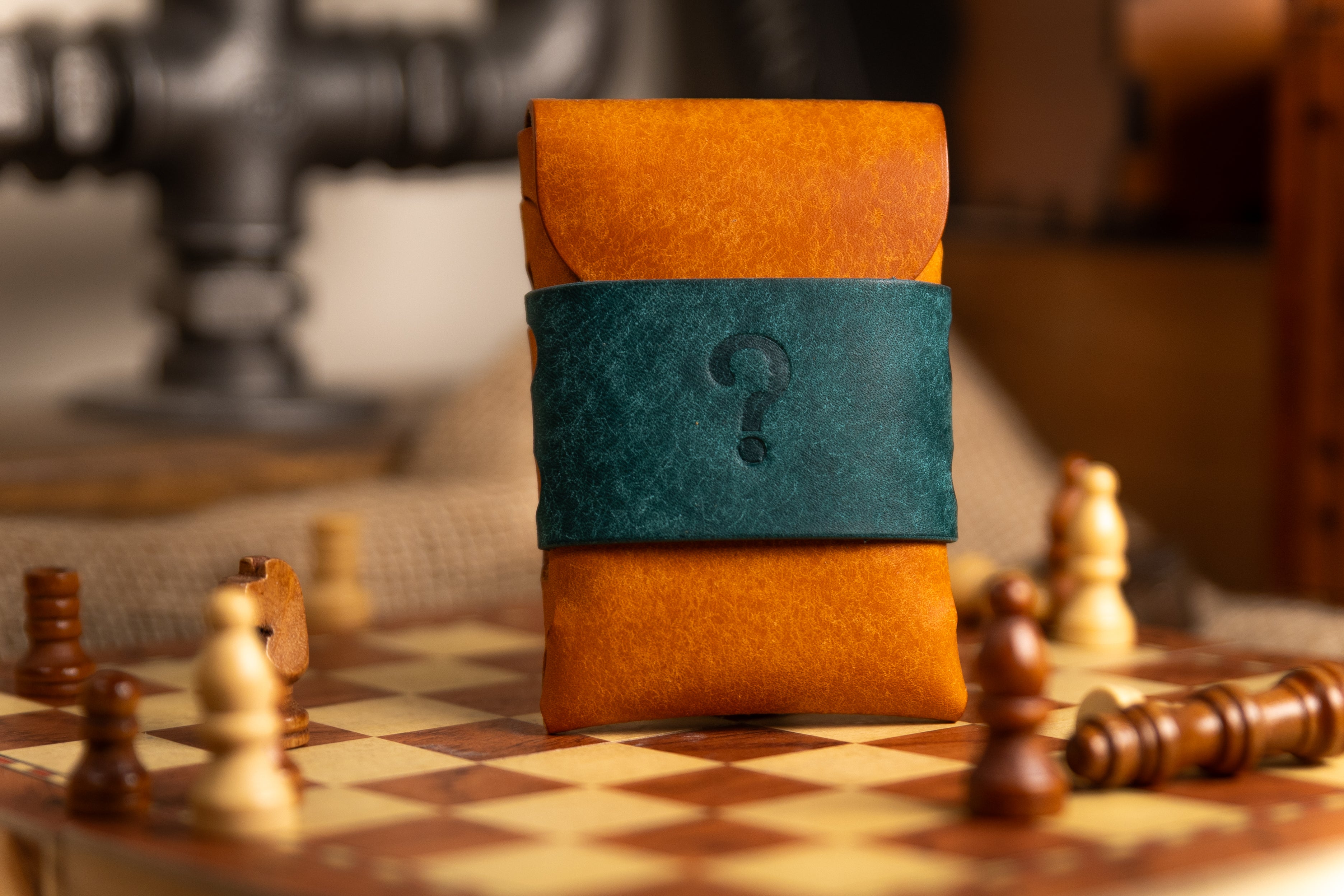Stack of brown leather-bound pueblo leather wallet with a blue spine featuring a question mark on a chessboard.