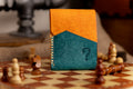 pueblo leather wallet with orange and blue design on a chessboard with chess pieces.