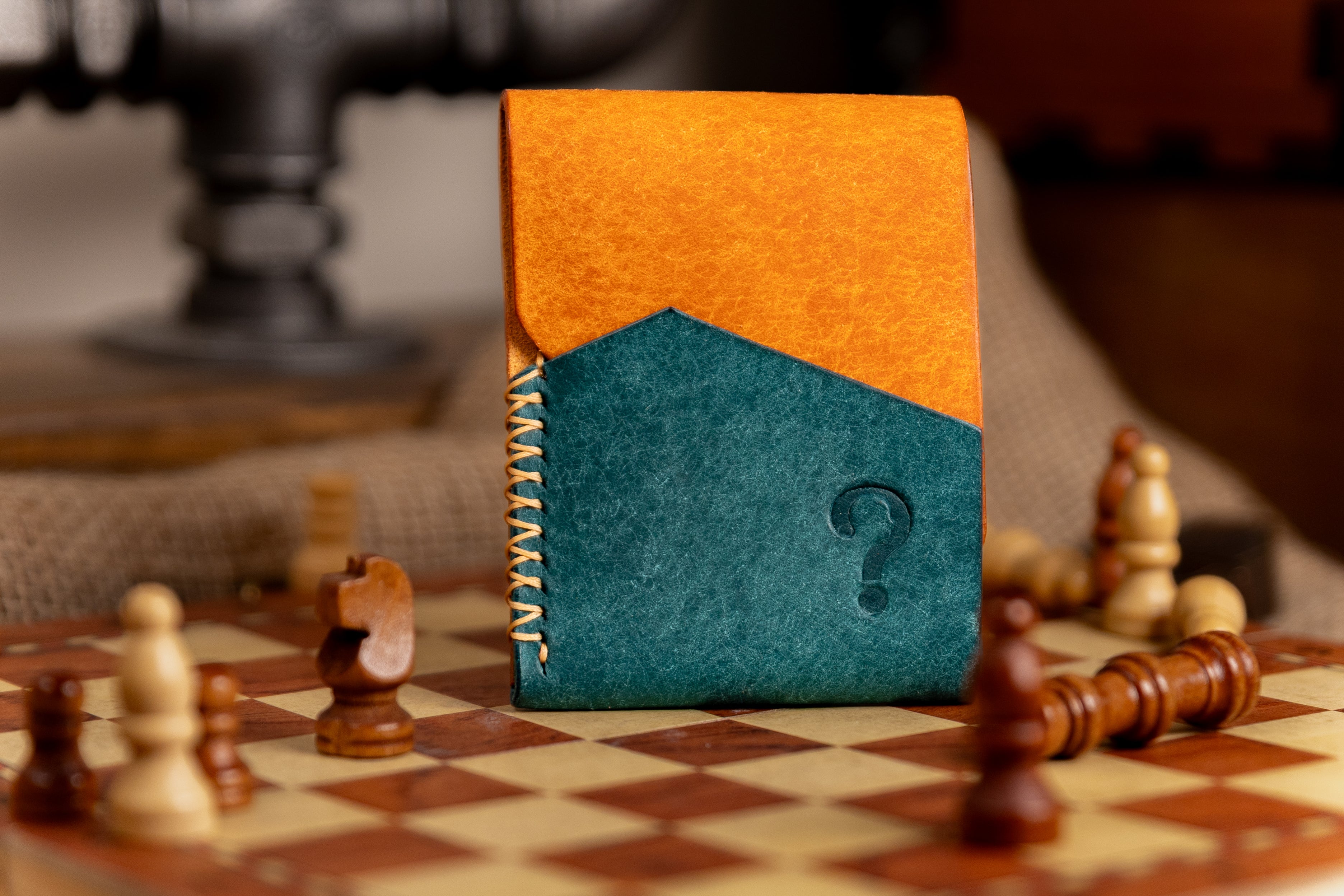 pueblo leather wallet with orange and blue design on a chessboard with chess pieces.