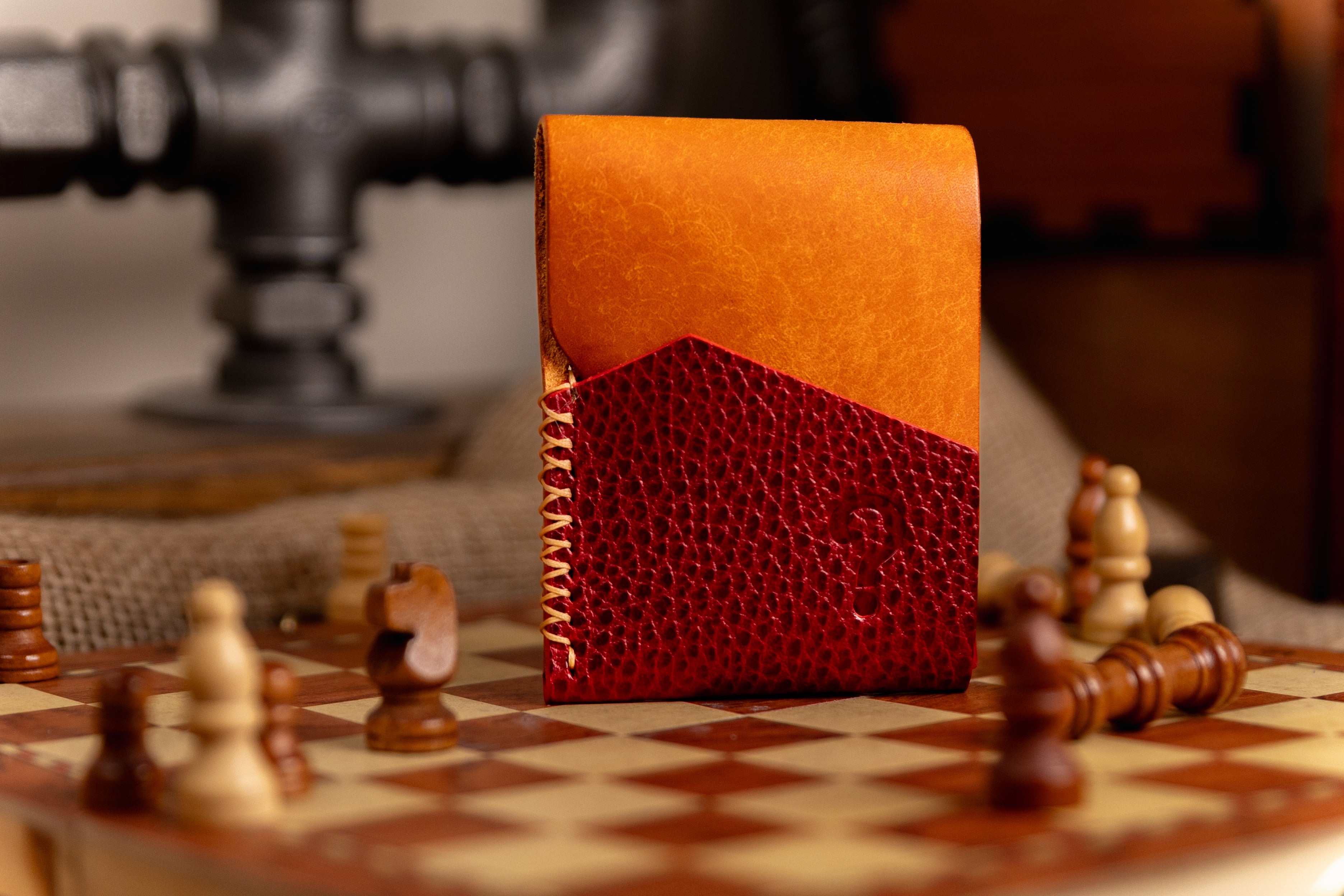 Orange and red leather wallet on a chessboard with chess pieces