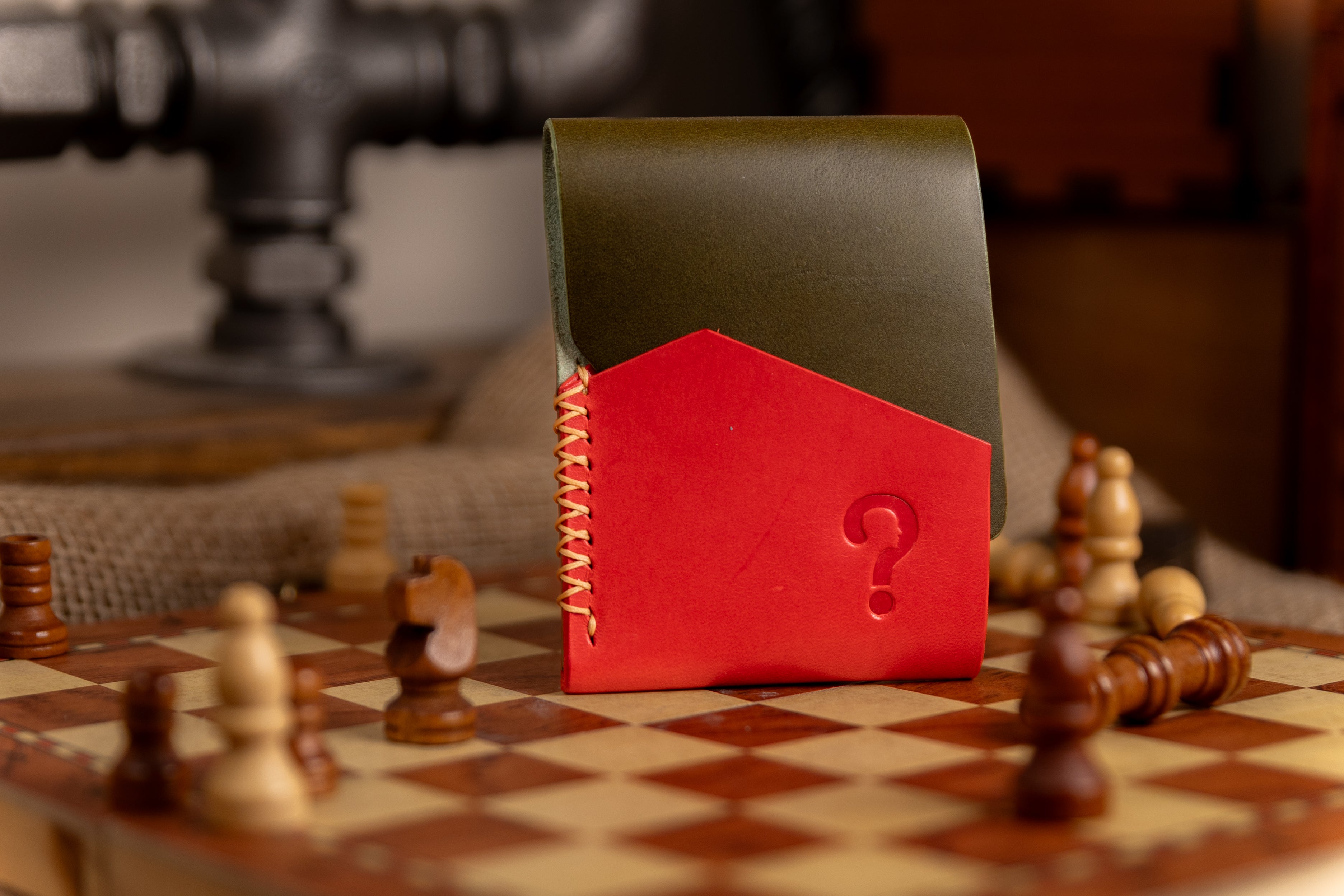 Red and green leather-bound book with a question mark on a chessboard