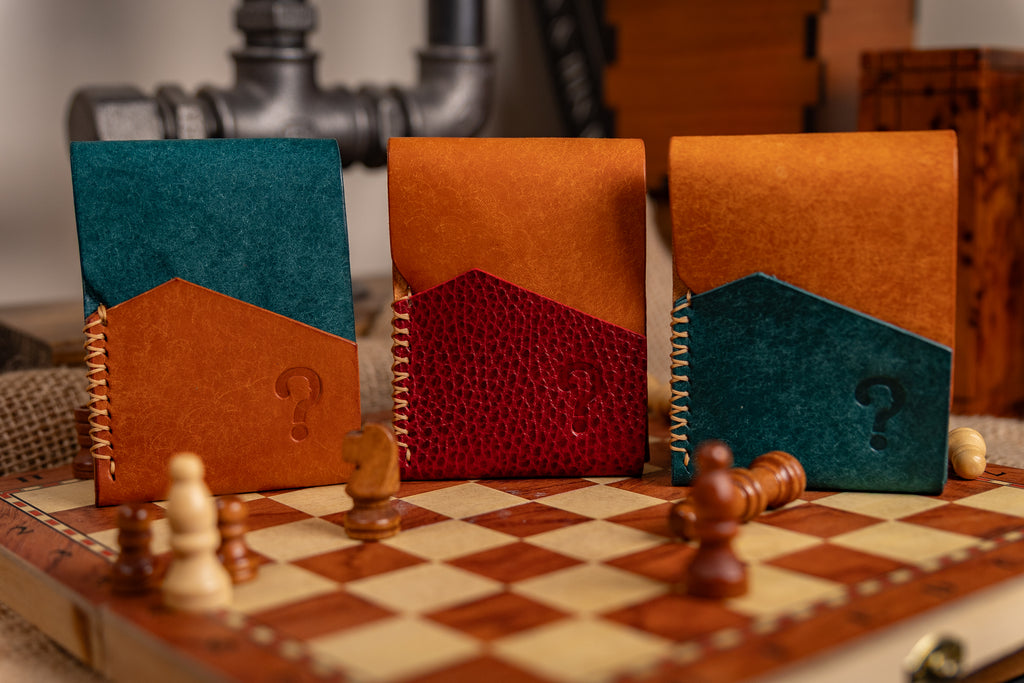 Three pueblo leather wallets with question marks on a chessboard