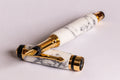 A luxury fountain pen with a white and gray marble-patterned resin body and polished gold-tone metal accents, shown on a clean light gray background.