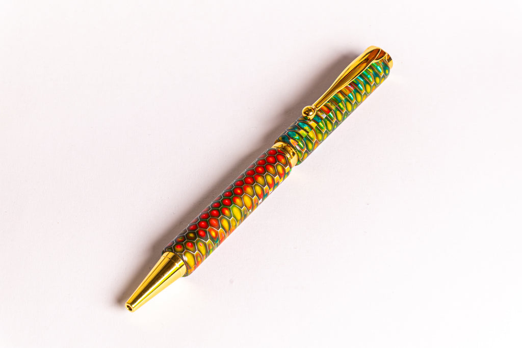 A gold-plated ballpoint pen with a vibrant, multicolored marbled pattern in red, green, yellow, and blue, shown diagonally on a plain white background.